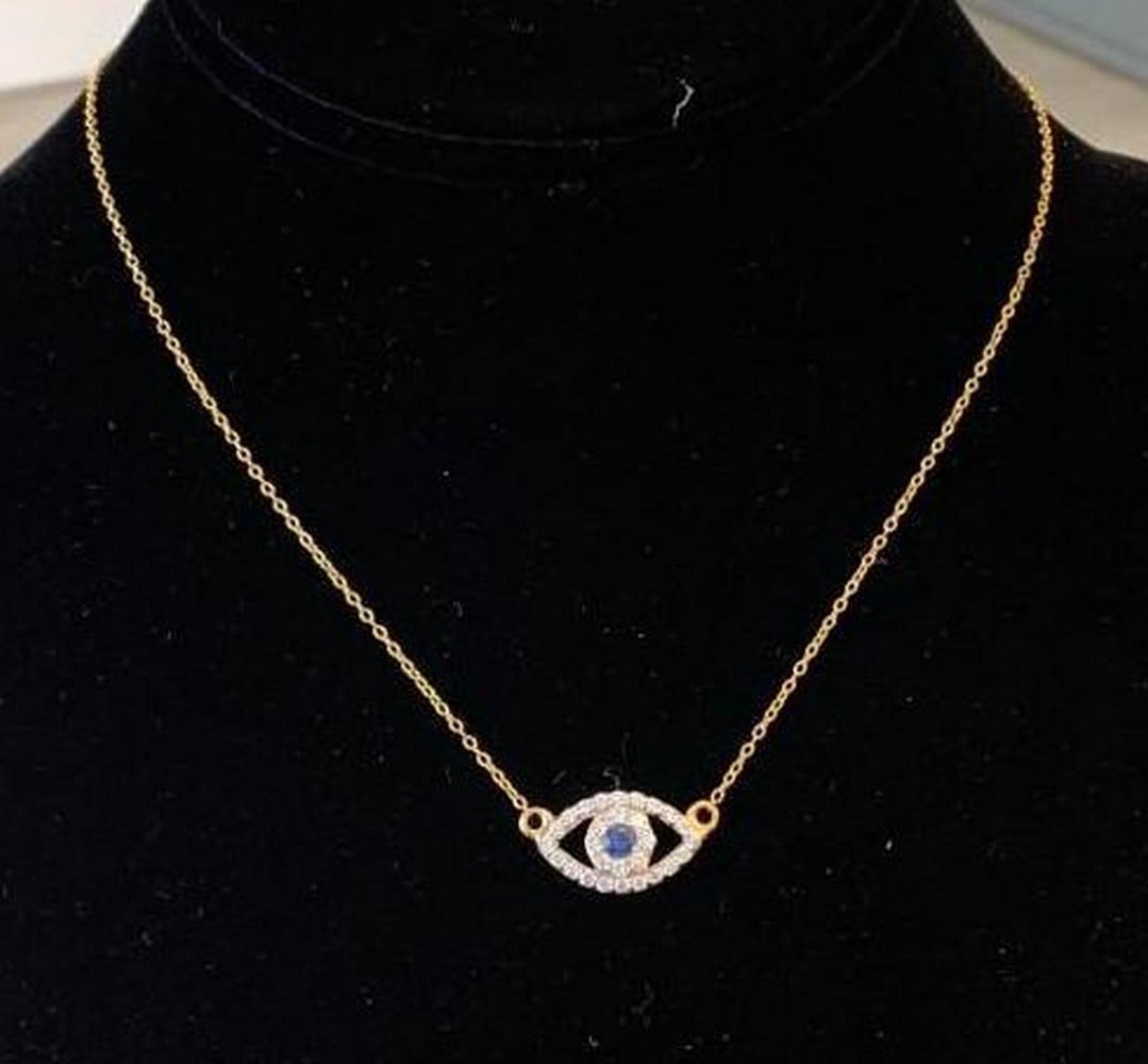 Sterling Silver Evil Eye Necklace: Sterling Silver Evil Eye Necklace This elegant necklace features a striking evil eye pendant crafted from gold-plated sterling silver. Sparkling blue and white gemstones accent the design, creating a