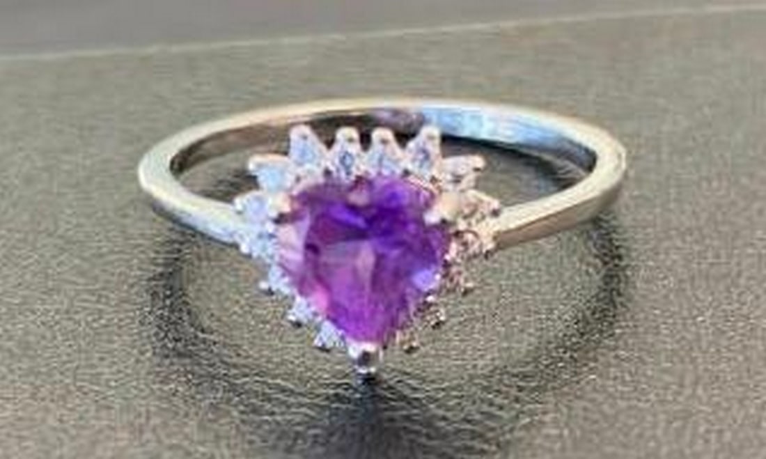 Sterling Silver Ring with Heart-Shaped Purple Stone: Sterling Silver Ring with Heart-Shaped Purple Stone This stunning sterling silver ring features a beautiful heart-shaped purple stone at its center, surrounded by a sparkling halo of clear crystals.