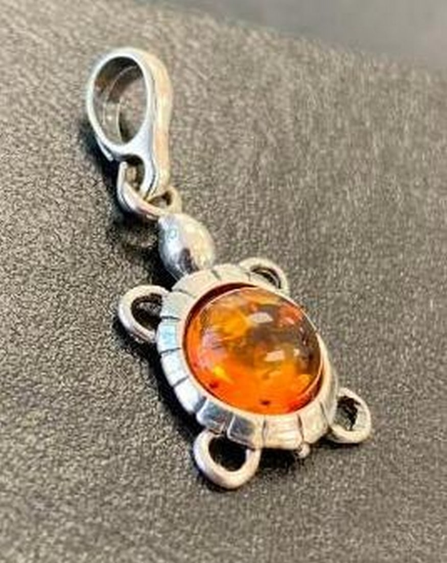 Amber Shell Turtle Charm: Amber Shell Turtle Charm This charming pendant features a beautifully detailed turtle design crafted in sterling silver, with a warm, glowing amber shell at the center. The natural amber adds depth
