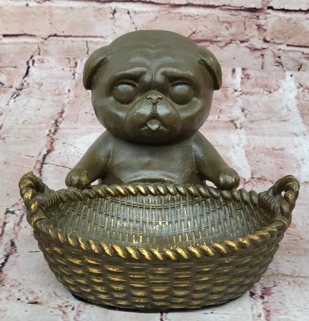 Bronze Pug with Basket Sculpture: Bronze Pug with Basket Sculpture Full of charm and character, this bronze sculpture bearing the signature of artist M. Lopez (Milo), features a delightful pug sitting upright with its tongue playfully
