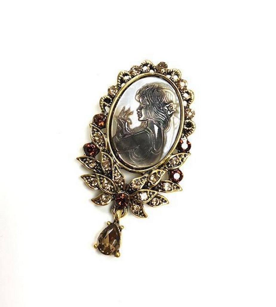 Red and Gold Rhinestone Fairy Cameo Brooch: Red and Gold Rhinestone Fairy Cameo Brooch This brooch features a fairy cameo silhouette. The perfect touch is the small dangle that lies below the cameo and the flower. Size: Approximately 2" L x