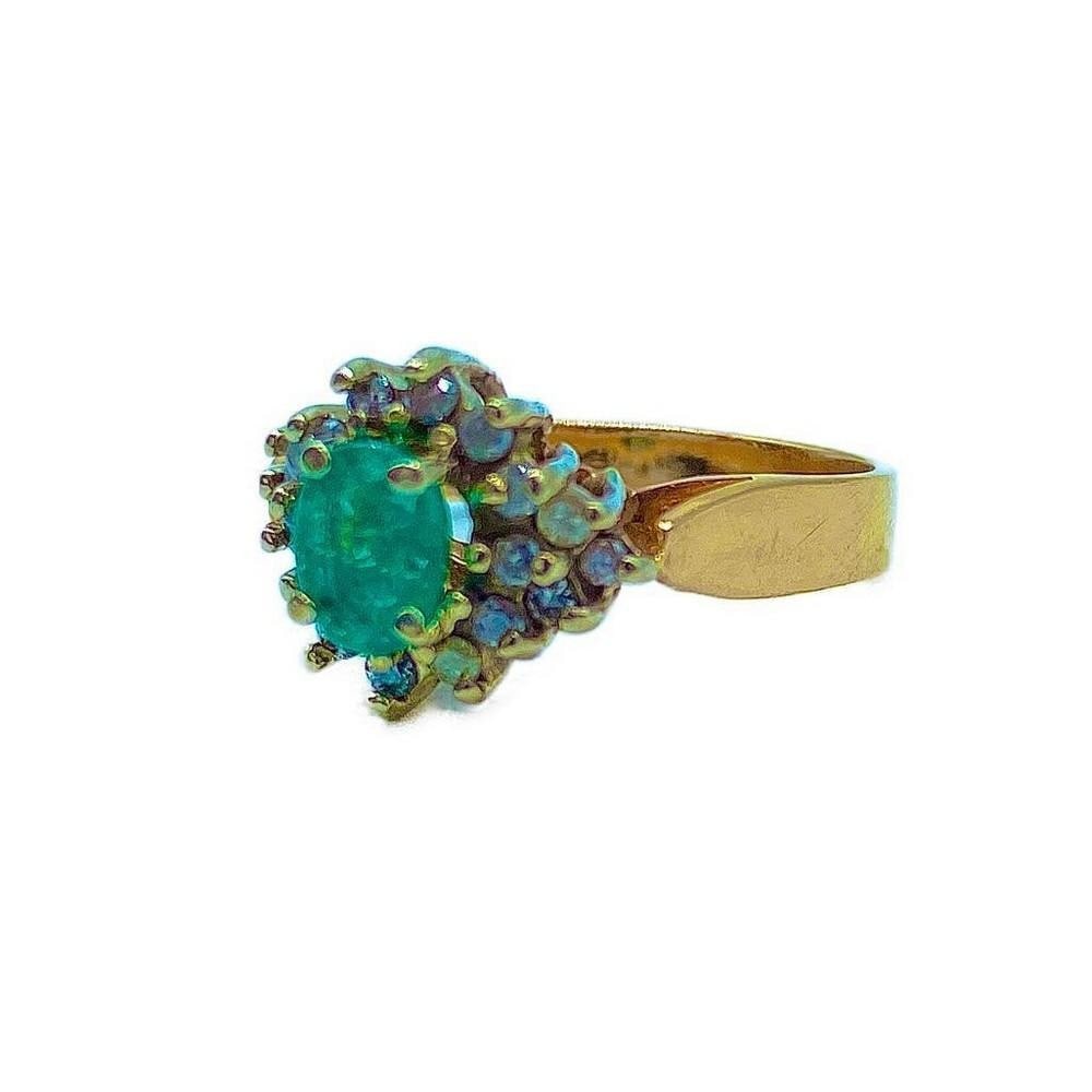 14K Gold Ring set with Oval Cut Emerald & Cubic Zirconia: 14K Gold Ring set with Oval Cut Emerald & Cubic Zirconia This ring is set with a 0.24ct Emerald stone and is surrounded by 18 round cut Cubic Zirconia stones. Dimensions of Emerald: 5.3 x 3.5 x 2.3mm