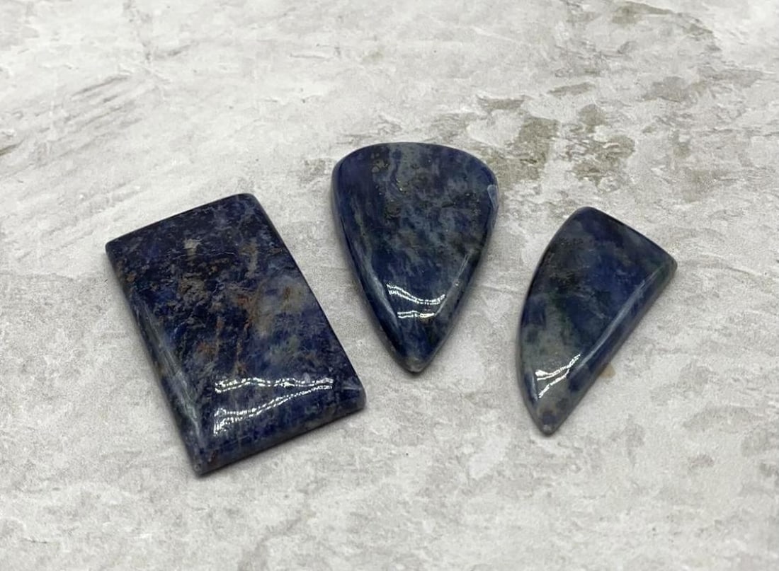 135ct Lot of 3 Blue Sodalite Stones: 135ct Lot of 3 Blue Sodalite Stones This striking 135-carat lot features three richly patterned blue sodalite stones, each showcasing a unique interplay of deep indigo, royal blue, and snowy white