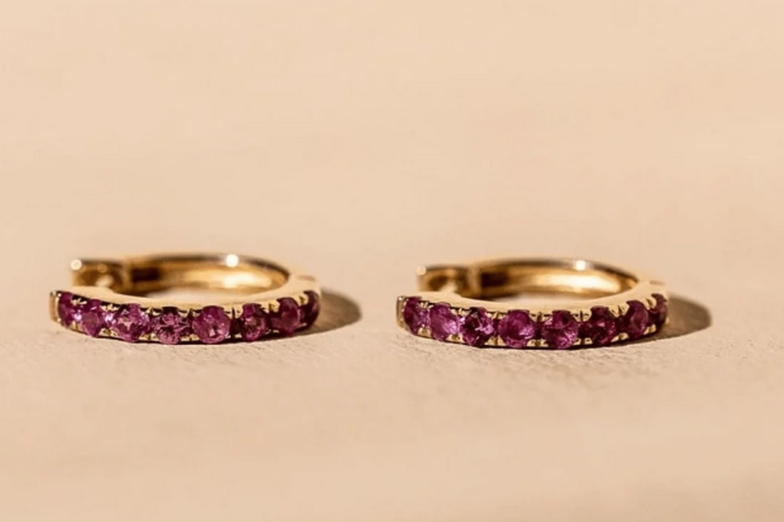 10k Solid Gold & Ruby Huggie Women's Earrings: 10k Solid Gold & Ruby Huggie Women's Earrings These 10K solid gold huggie earrings showcase a captivating blend of elegance and charm. Adorned with radiant ruby gemstones, their sleek, close-f