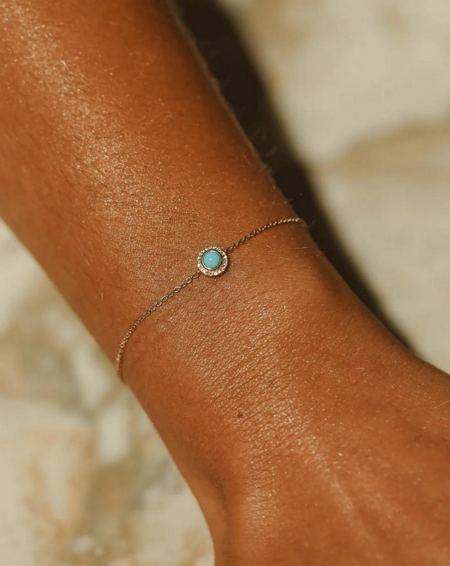 14k Solid Gold Turquoise Halo Bracelet: 14k Solid Gold Turquoise Halo Bracelet Enhance your bracelet collection with the radiant glow of iridescence. This piece features a round turquoise encircled by pavé sapphires, all set in 14k solid