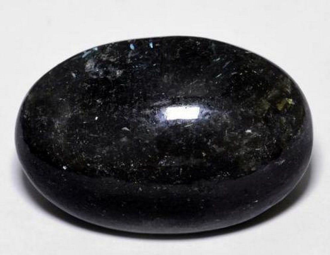 23.7ct Oval Cabochon Black with Blue Sparkle Nuummite Gemstone: 23.7ct Oval Cabochon Black with Blue Sparkle Nuummite Gemstone Discover the mesmerizing 23.7ct Oval Cabochon Black with Blue Sparkle Nuummite Gemstone, a captivating treasure of the Earth. This enchan