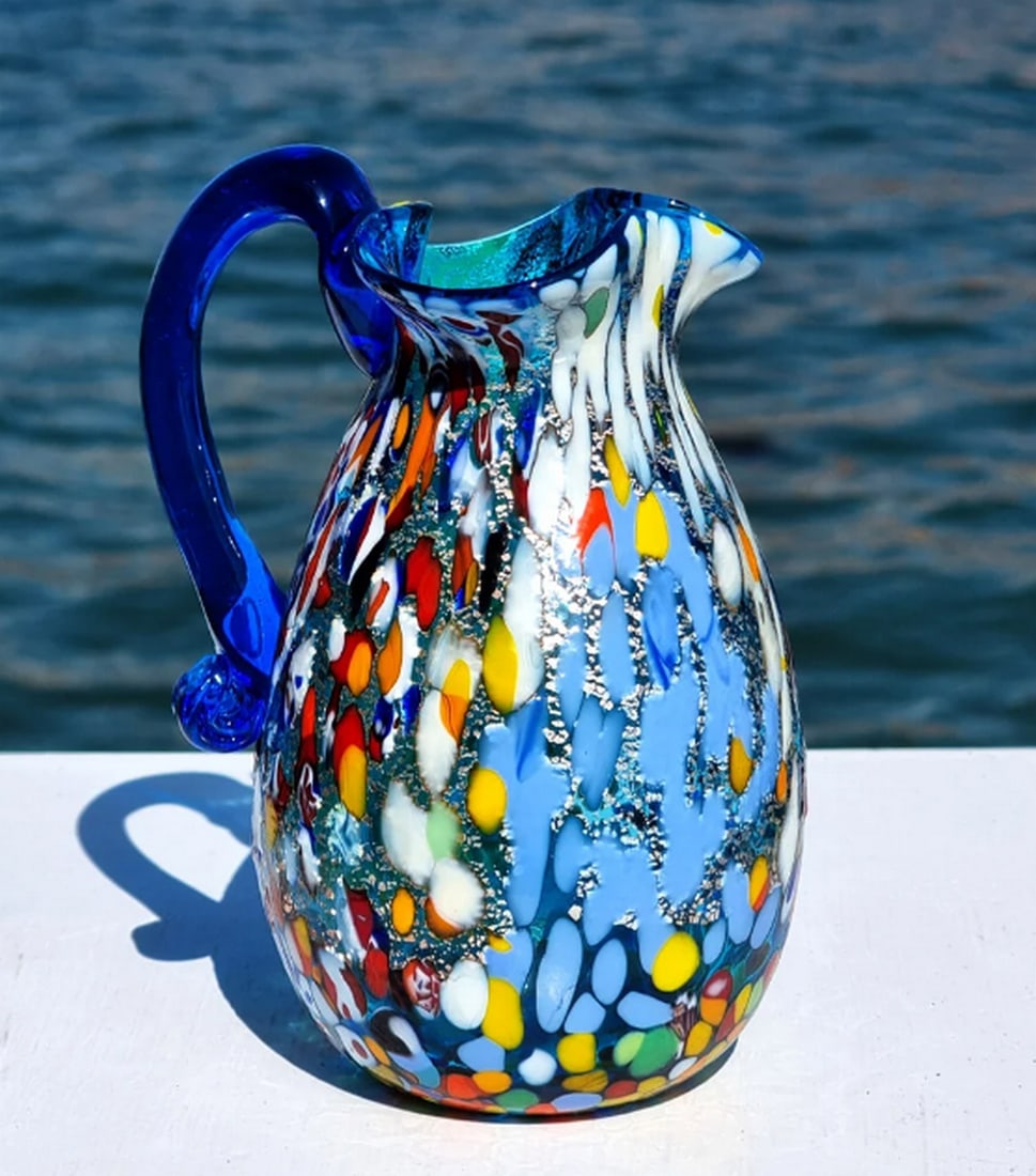 Blue Millefiori Murano Glass Carafe: Blue Millefiori Murano Glass Carafe This carafe is expertly crafted using glassblowing techniques, featuring silver and murrina decorations. It has a capacity of approximately 60 cl and is signed by M