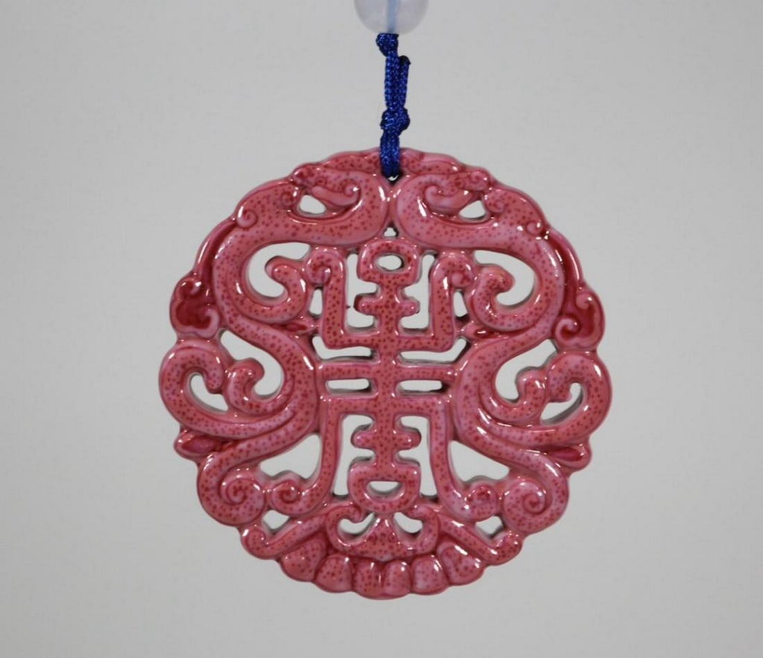 Carmine Red Porcelain Pendant with Carved Longevity Character: Carmine Red Porcelain Pendant with Carved Longevity Character A finely crafted porcelain pendant inspired by the Qing Dynasty, glazed in a rich carmine red tone and featuring a meticulously carved