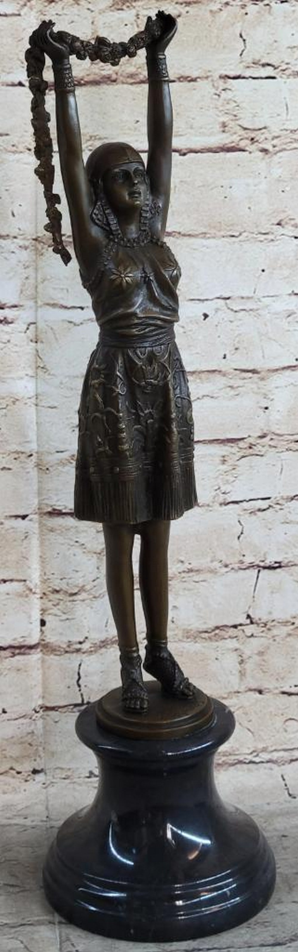 Flower Dancer Inspired Bronze Statue - 19'' x 5'': Flower Dancer Inspired Bronze Statue - 19" x 5" She stands on tiptoes, arms outstretched to offer a beautifully strung arrangement of flowers. Her dress, adorned with intricate floral patterns