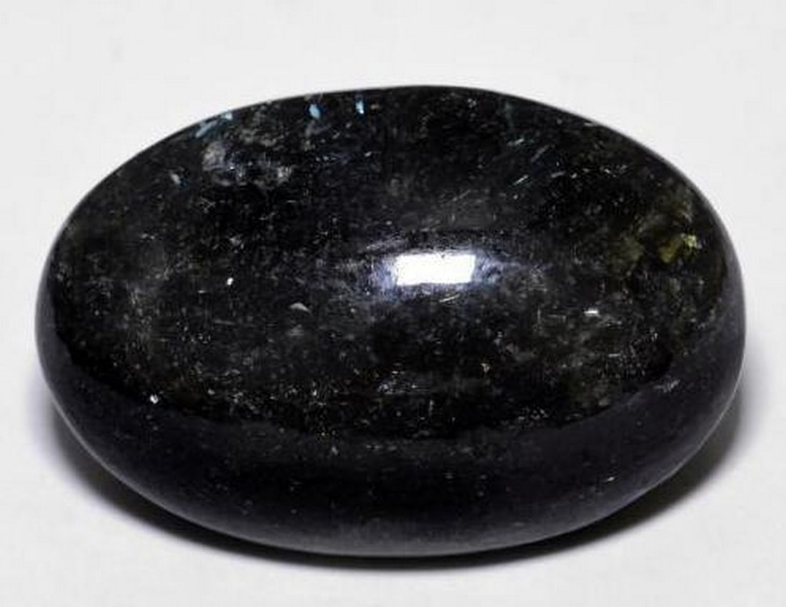 23.7ct Oval Cabochon Black with Blue Sparkle Nuummite Gemstone: 23.7ct Oval Cabochon Black with Blue Sparkle Nuummite Gemstone Discover the mesmerizing 23.7ct Oval Cabochon Black with Blue Sparkle Nuummite Gemstone, a captivating treasure of the Earth. This enchan