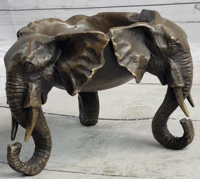 Trinity of Wisdom: Bronze Elephant Head Dish: Trinity of Wisdom: Bronze Elephant Head Dish A captivating fusion of form and function, this bronze sculpture dish features three intricately carved elephant heads encircling the sides. Each noble hea