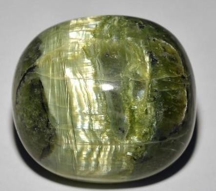 32.45ct Oval Cabochon Moss Green Cat's Eye Opal Gemstone: 32.45ct Oval Cabochon Moss Green Cats Eye Opal Gemstone Introducing the Oval Cabochon Moss Green Cats Eye Opal Gemstone-a celestial marvel that captures the mysterious allure of moonlit meadows. The