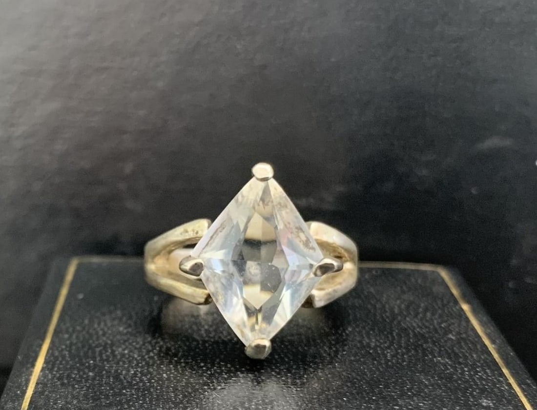 Silver-Tone Ring with Large Diamond-Shaped Clear Stone: Silver-Tone Ring with Large Diamond-Shaped Clear Stone Make a bold statement with this elegant silver-toned ring, featuring a large diamond-shaped clear stone as its centerpiece. The bright, faceted