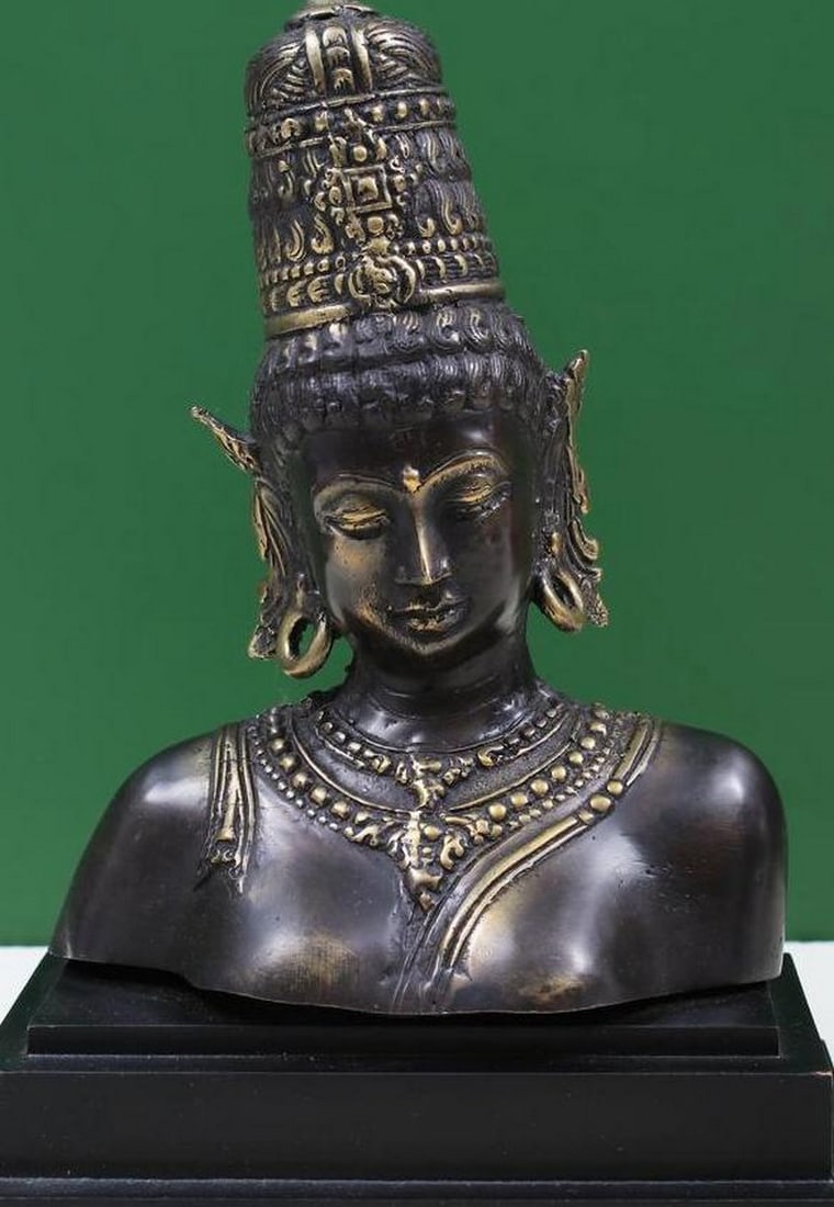7" Goddess Parvati Bust on Wooden Stand: 7" Goddess Parvati Bust on Wooden Stand This 7" brass bust beautifully depicts Goddess Parvati, the divine mother and consort of Lord Shiva, exuding serenity and divine grace. Her downcast eye