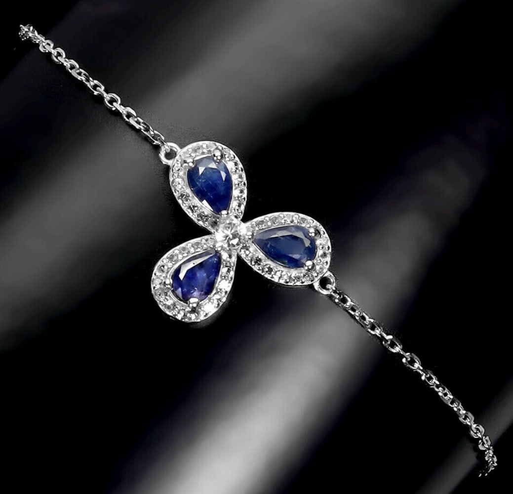 Rich Blue Sapphire and White Topaz Petal Bracelet: Rich Blue Sapphire and White Topaz Petal Bracelet This exquisite bracelet features a cascade of three petal-like pear-shaped blue sapphire gemstones, arranged in a floral-inspired design. Each sapphir