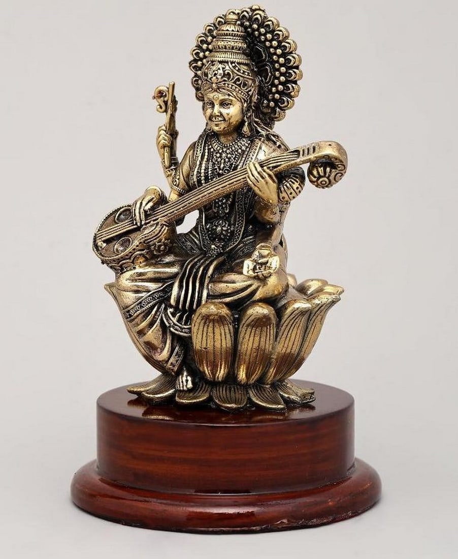 5" Small Brass Goddess Saraswati Seated on Lotus with Veena on Wooden Base: 5" Small Brass Goddess Saraswati Seated on Lotus with Veena on Wooden Base This 5" brass idol beautifully depicts Goddess Saraswati, the Hindu deity of knowledge, music, art, and wisdom, seate