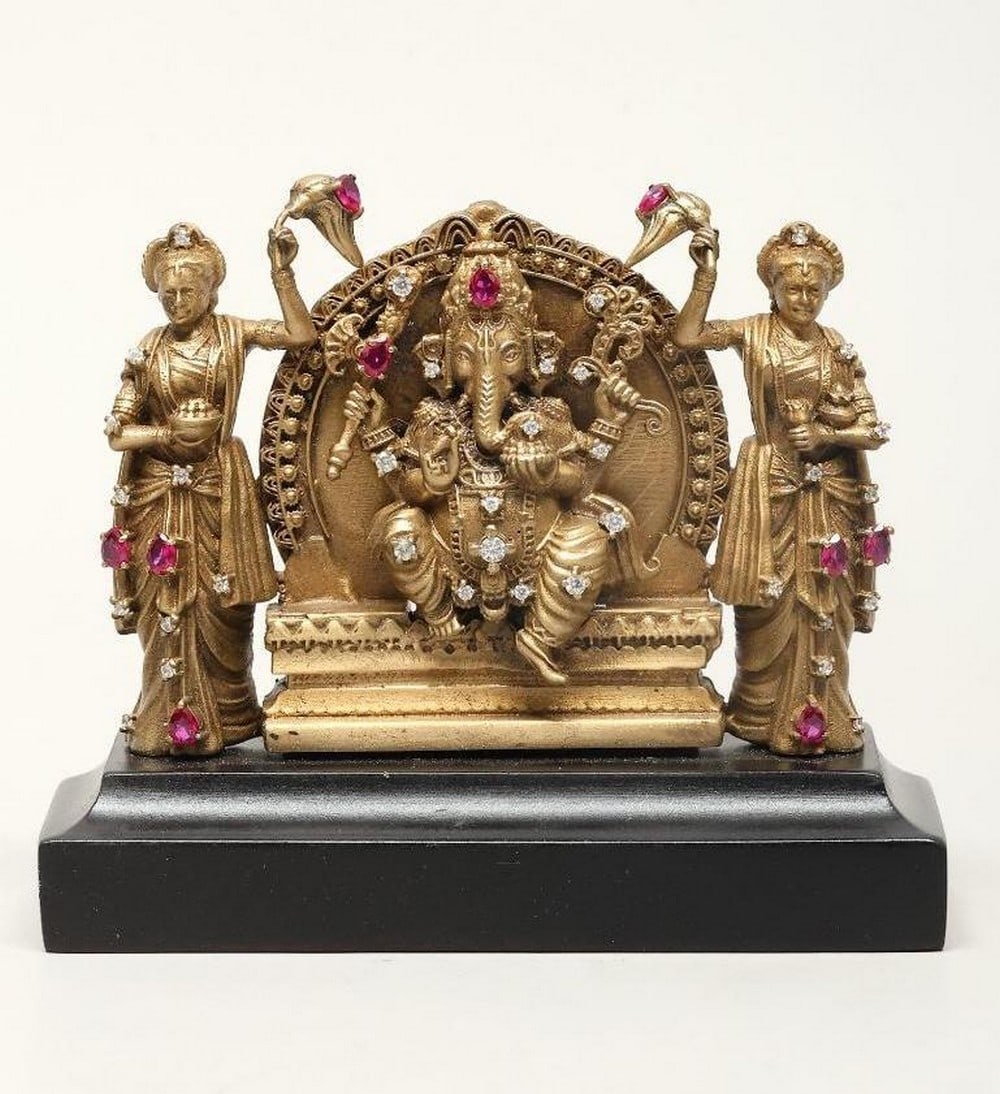 3" Small Seated Lord Ganapati with Riddhi and Siddhi: 3" Small Seated Lord Ganapati with Riddhi and Siddhi This brass statue depicts Lord Ganesha, the remover of obstacles and embodiment of wisdom, prosperity, and good fortune, seated in a relaxed po