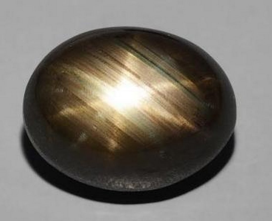 Loose Black Star Sapphire: Loose Black Star Sapphire Mysterious and captivating, this loose black Star Sapphire features a smooth oval cabochon shape that beautifully reveals its natural star-like asterism under direct light. T