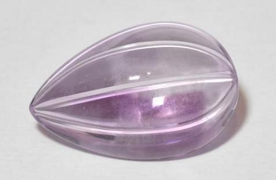Pinkish Violet Amethyst Carved Pear Gemstone: Pinkish Violet Amethyst Carved Pear Gemstone This captivating loose gemstone is carved into an elegant pear shape from natural amethyst, showcasing a stunning pinkish violet hue. The gentle blend of p