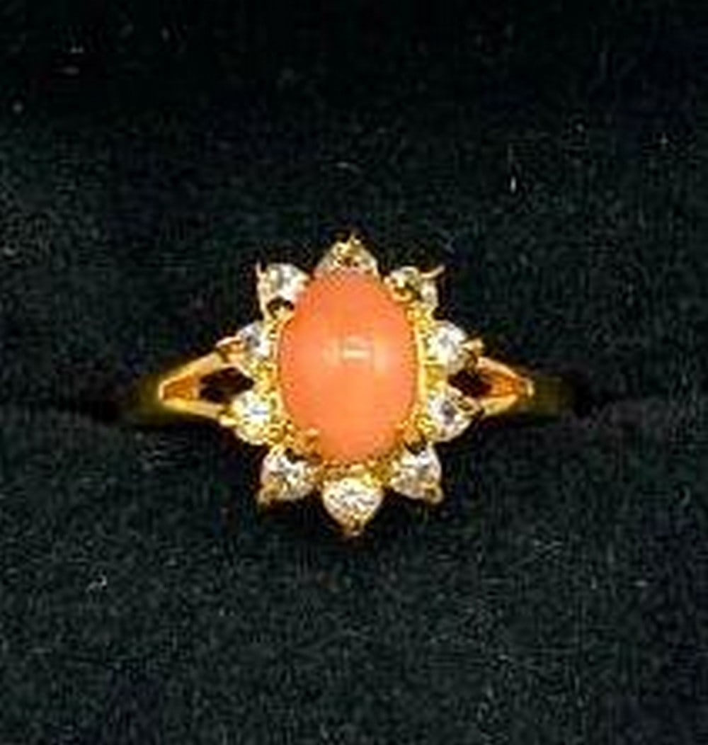 Glorious Coral Stone Halo Ring in 18KT Gold Electroplate Finish: Glorious Coral Stone Halo Ring in 18KT Gold Electroplate Finish A stunning blend of warmth and brilliance, this ring showcases a vivid coral stone at its center, surrounded by a radiant halo of white 