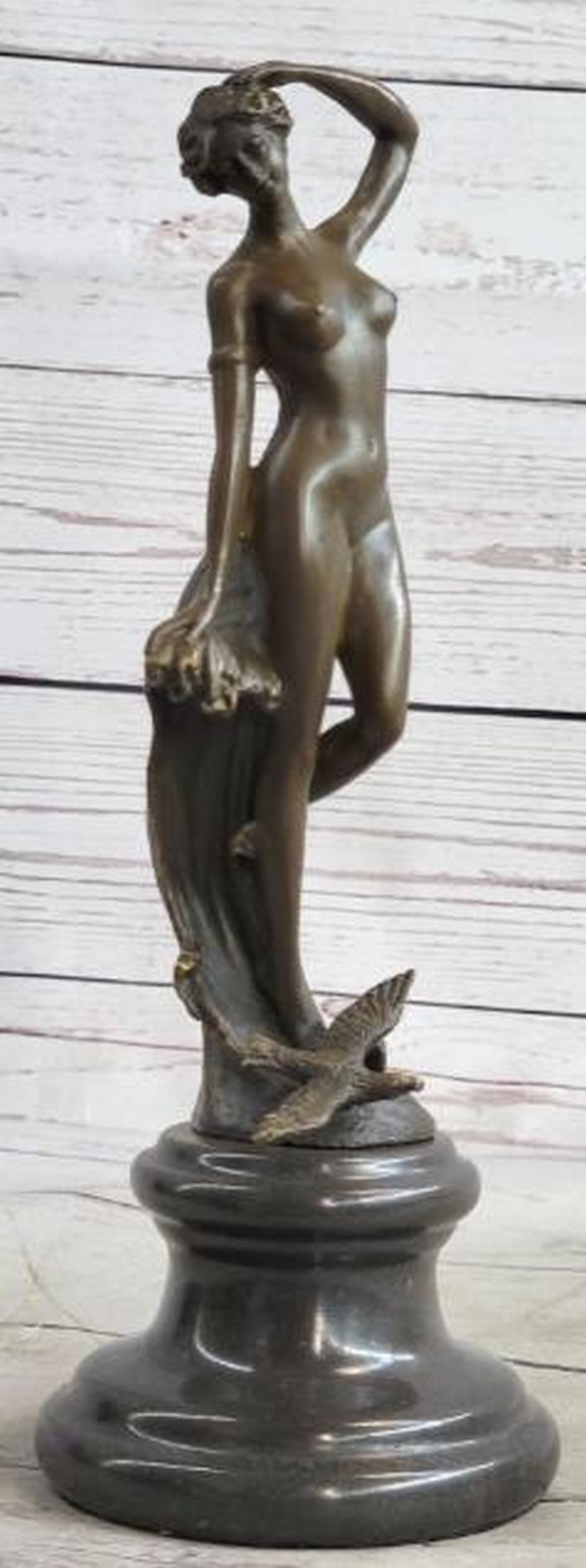Nude Woman Among Waves Bronze Sculpture: Nude Woman Among Waves Bronze Sculpture Sensual and fluid, this bronze sculpture depicts a nude female figure gracefully emerging from stylized ocean waves. With one hand resting gently atop her head 