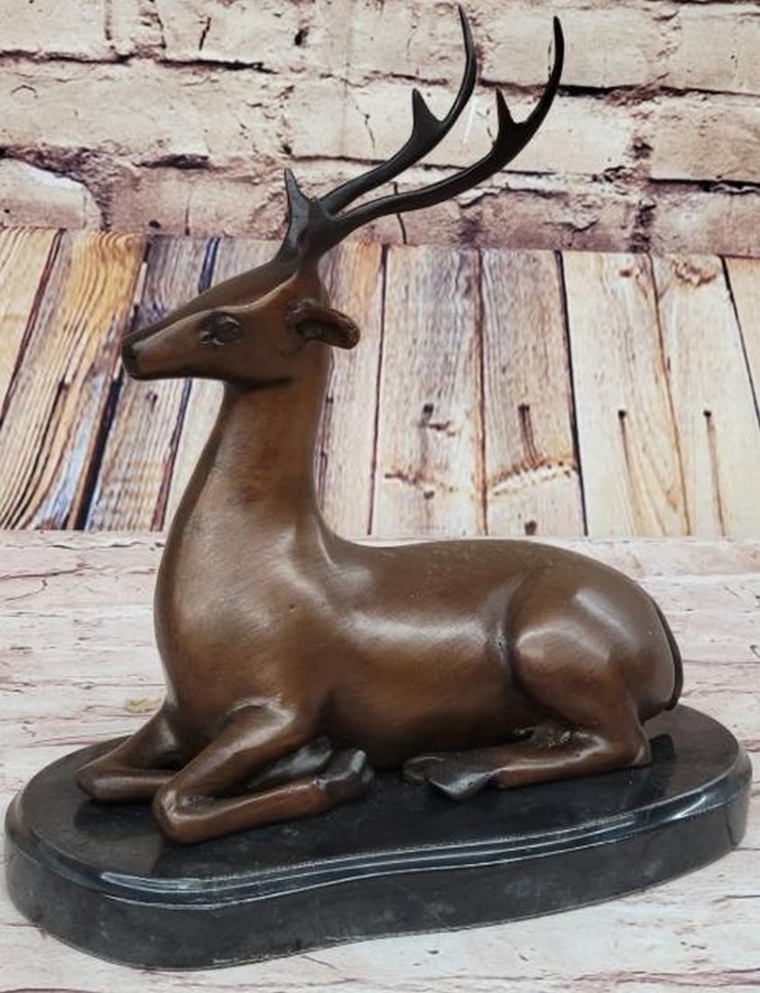 Bronze Reclining Deer Sculpture: Bronze Reclining Deer Sculpture This elegant bronze sculpture, bearing the signature of artist Milo, captures a reindeer (or caribou, deer, or elk) at rest, yet fully alert. Lying gracefully with its 