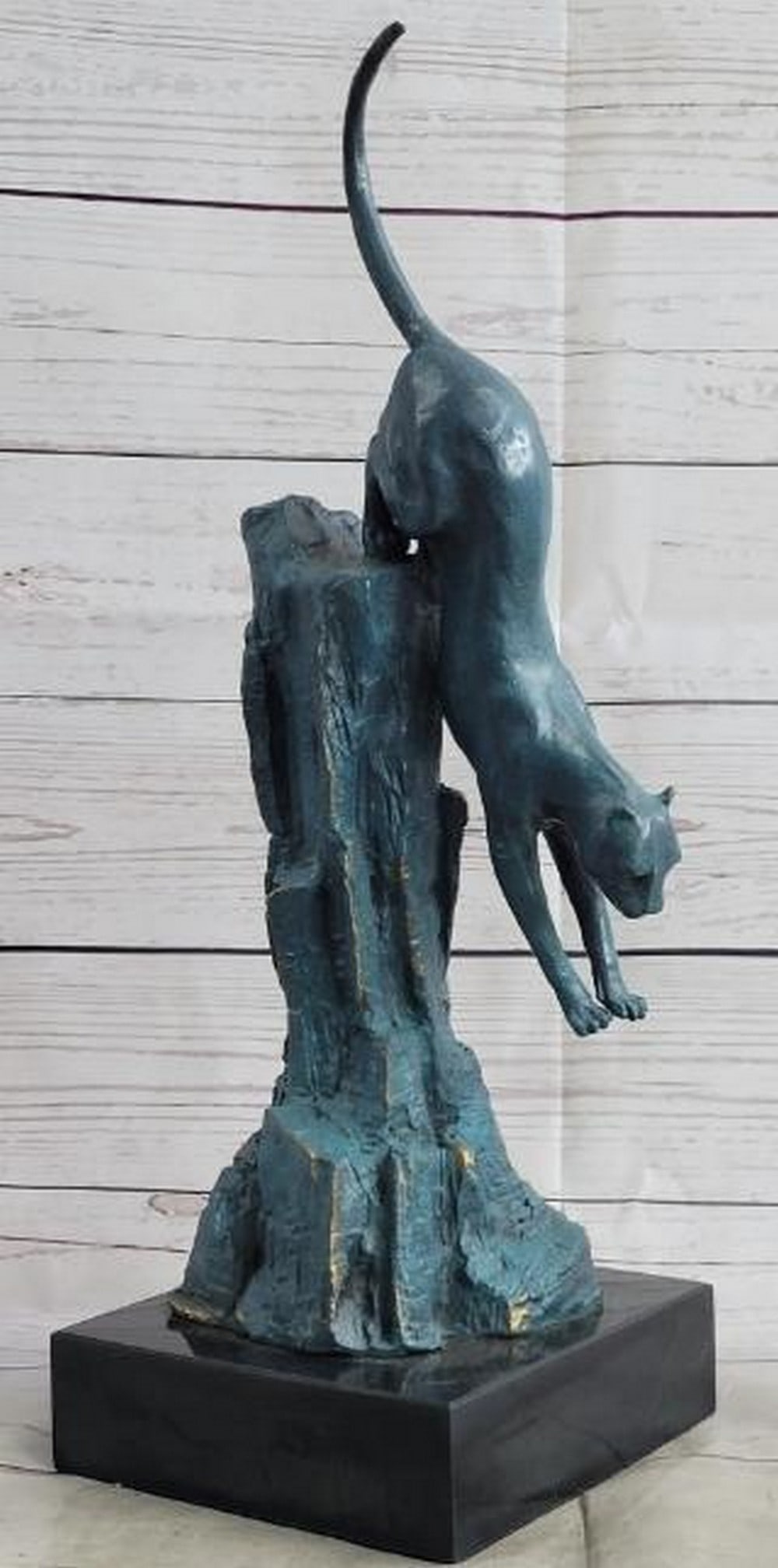 Blue Patina Bronze Cougar Sculpture: Blue Patina Bronze Cougar Sculpture Captured in a breathtaking display of motion and power, this bronze sculpture features a cougar mid-pounce, its body fully stretched as it launches downward from th