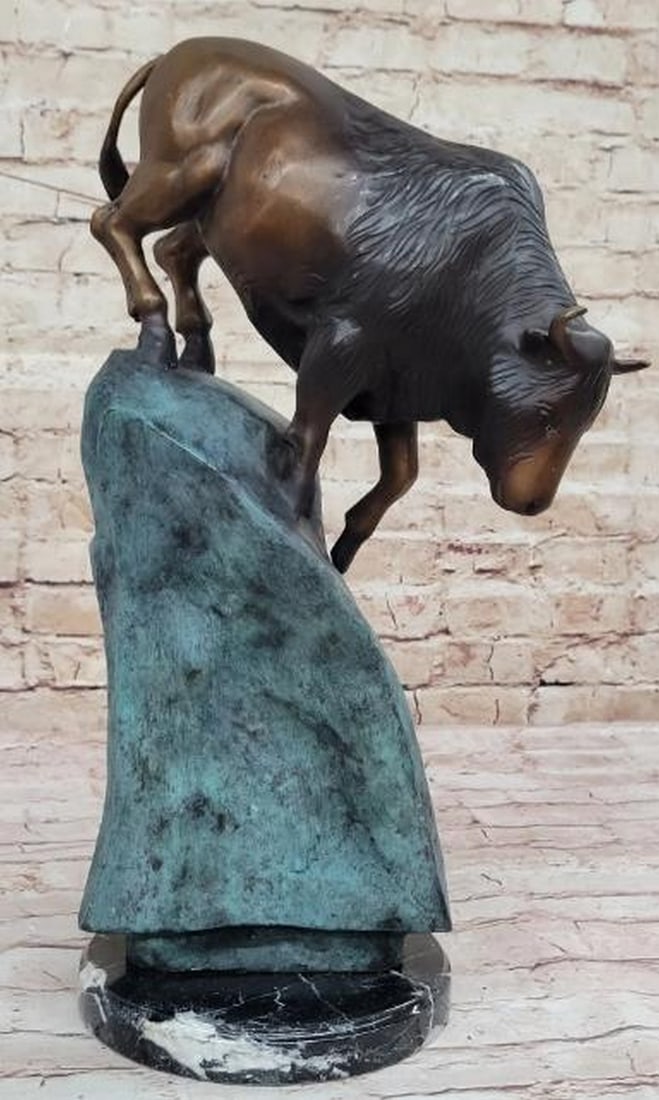 Hot Cast Bronze Bison on Blue Patina Base: Hot Cast Bronze Bison on Blue Patina Base Commanding and full of motion, this hot cast bronze sculpture captures a powerful bison in mid-descent, carefully navigating a rugged, rock-like base finished