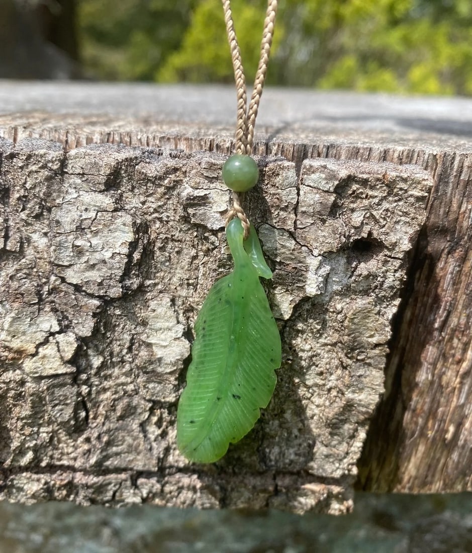 Canadian Nephrite Jade Feather Pendant: Canadian Nephrite Jade Feather Pendant This pendant is hand-carved from genuine Canadian Nephrite Jade, shaped into a delicate feather design that symbolizes freedom and spiritual connection. The poli