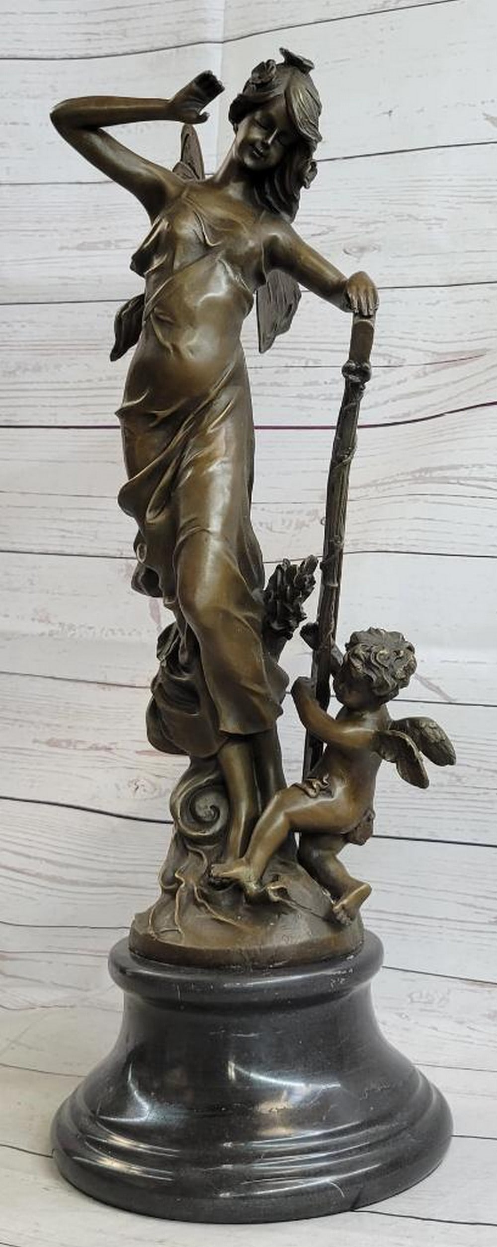 Flying Winged Fairy Bronze Sculpture On Marble Base - 25lbs: A young cherub reaches to a fairy to gain her attention. The beautiful fairy reaches back to the cherub with a delicate to his playful curls. She's holding a musical Harps in this enchanting sculpture