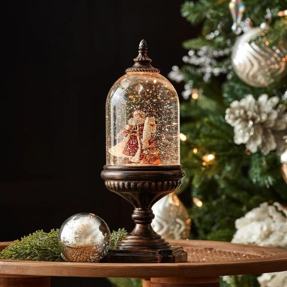 Lighted Santa Snow Globe: Lighted Santa Snow Globe Illuminate your home this holiday season with this charming Lighted Snow Globe. Featuring a traditional Santa scene with a toy bag accent inside a vintage bell jar, the
