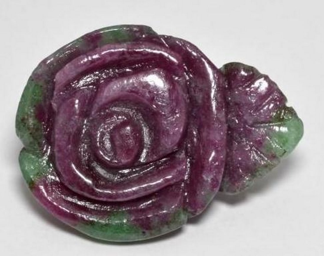 Ruby-Zoisite Rose Carved Gemstone: Ruby-Zoisite Rose Carved Gemstone This beautifully hand-carved loose gemstone features a blooming rose design sculpted from natural Ruby-Zoisite. A captivating blend of rich red and purple tones from