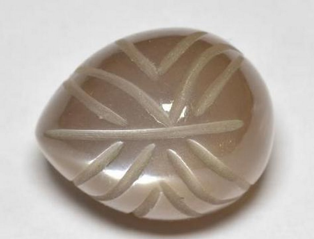 Medium Brown Moonstone Carved Leaf Gemstone: Medium Brown Moonstone Carved Leaf Gemstone Gracefully shaped into a delicate leaf, this loose gemstone is carved from medium brown moonstone, showcasing a soft, earthy shimmer with subtle flashes of