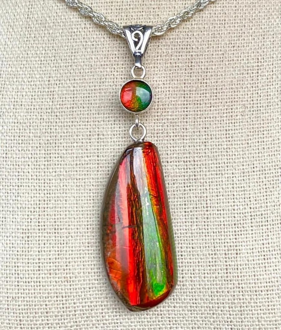 Vibrant Red & Green Ammolite Pendant with Color-Changing Triplet Accent: Vibrant Red & Green Ammolite Pendant with Color-Changing Triplet Accent This ammolite pendant features a striking, chunky red and green gem that shifts to a deeper green at extreme angles. The gem