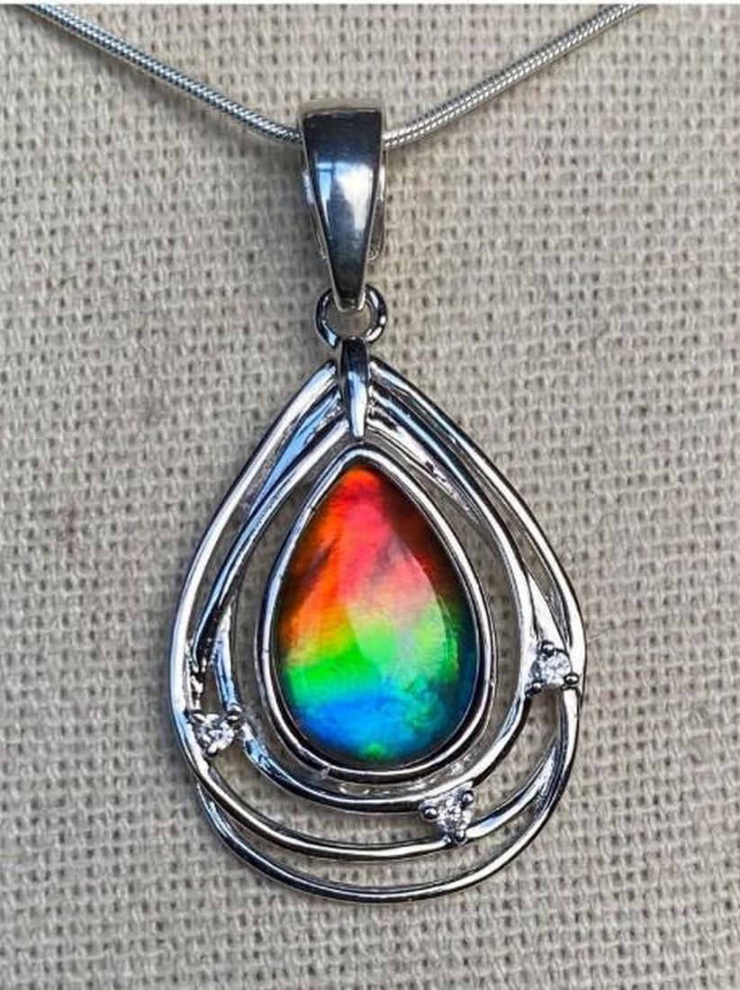 Solara Petite Ammolite Pendant: Solara Petite Ammolite Pendant The Solara Petite Ammolite Pendant radiates warmth and brillance in a delicate design. Its vibrant hues dance with light, capturing the fiery essence of the sun in a com