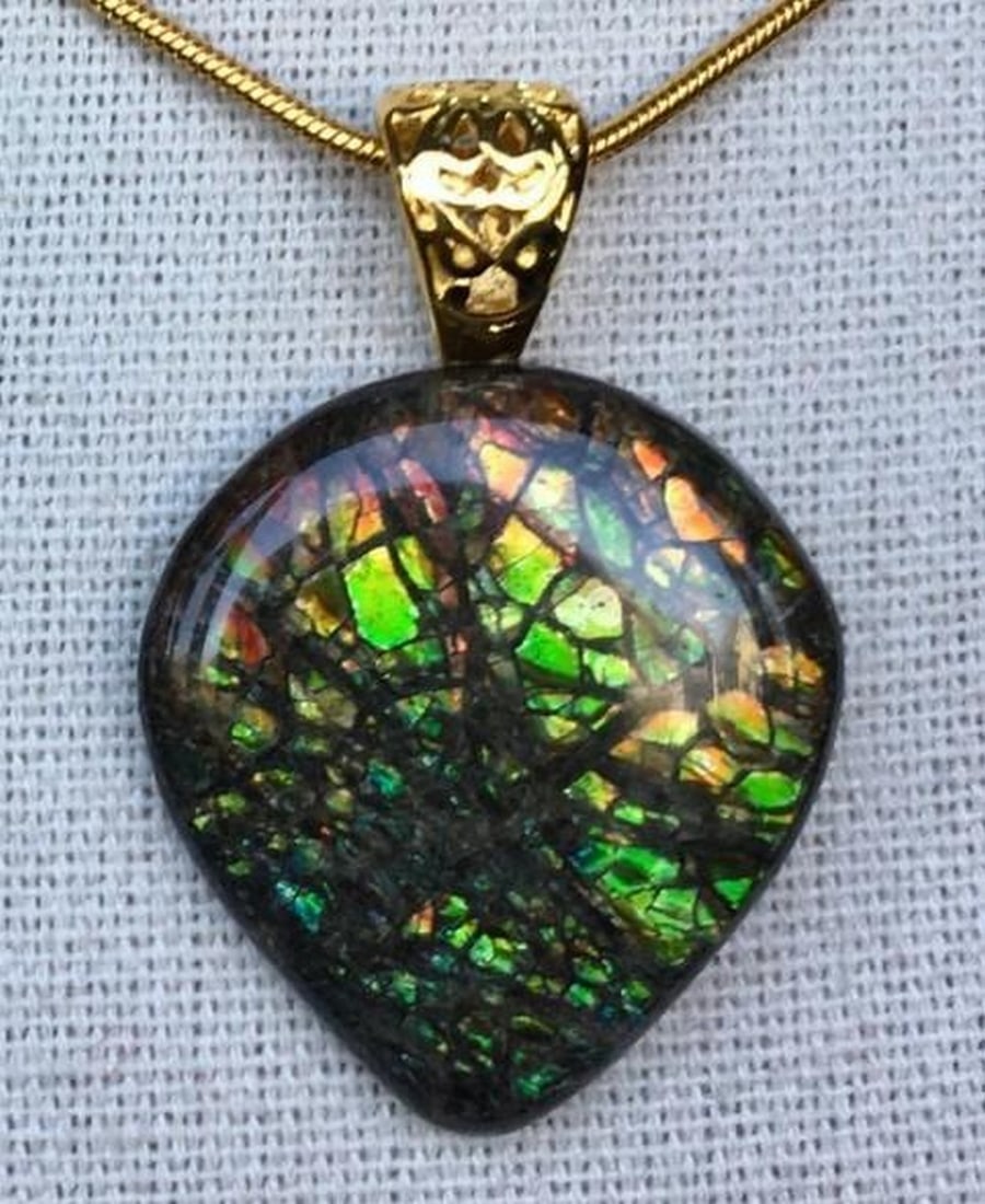 Mystic Inferno Ammolite Pendant: Mystic Inferno Ammolite Pendant This is an ammolite pendant with a gemstone in subdued autumn colors. The stone hangs from a gold plated bail, and measures in at 26mm x 24mm. It comes on an 18 gold