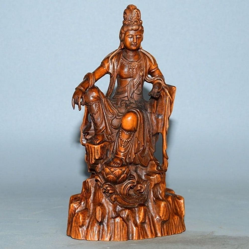 Wood Carved Guanyin Buddha Statue: Wood Carved Guanyin Buddha Statue This beautifully carved wood statue depicts Guanyin, the Bodhisattva of Compassion, seated in a calm and meditative posture. Every detail, from the flowing robes to t