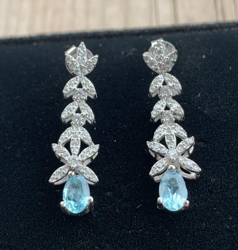 Oval Apatite Stud Earrings in Sterling Silver: Oval Apatite Stud Earrings in Sterling Silver These elegant earrings feature 6x4mm oval-cut natural apatite gemstones, set in polished 925 sterling silver. The vibrant blue-green hues of the apatite b