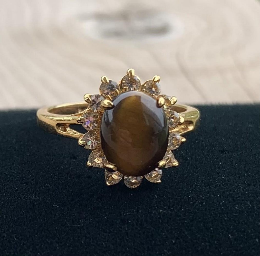 Golden Tiger's Eye Statement Ring: Golden Tiger's Eye Statement Ring This striking ring by Dolphin Ore features a polished tiger's eye gemstone, known for its rich golden-brown bands and natural chatoyancy. Set in a warm gold-tone band
