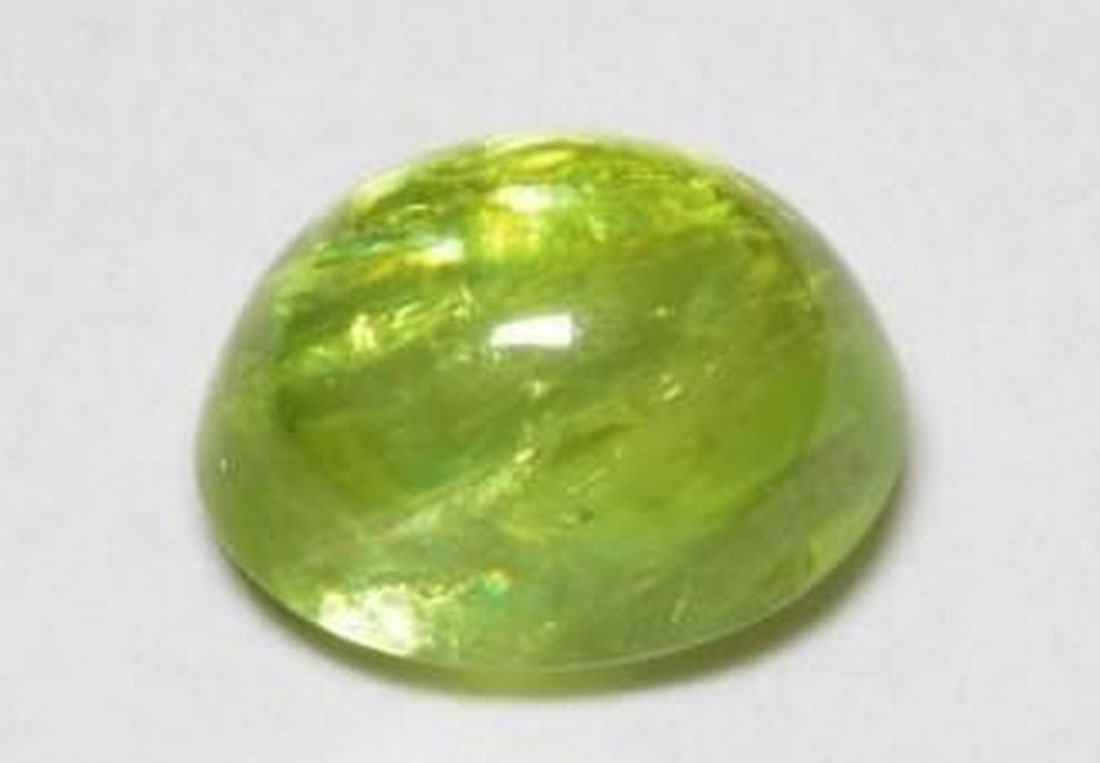 1.25ct Oval Green Sphene Gemstone with Fire: 1.25ct Oval Green Sphene Gemstone with Fire This 1.25ct natural sphene captivates with its medium green hue and brilliant internal fire. Expertly cut into an oval shape, the transparent gem dazzles