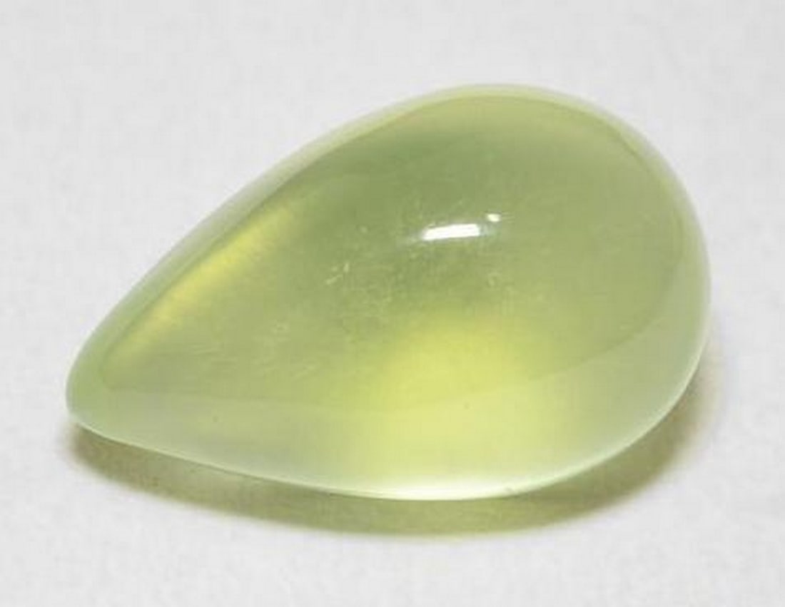 7.3ct Pear Cabochon Sour Lime Green Prehnite Gemstone: 7.3ct Pear Cabochon Sour Lime Green Prehnite Gemstone Introducing the refreshing elegance of our 7.3ct Pear Cabochon Sour Lime Green Prehnite Gemstone. Crafted to perfection, its smooth and polished s