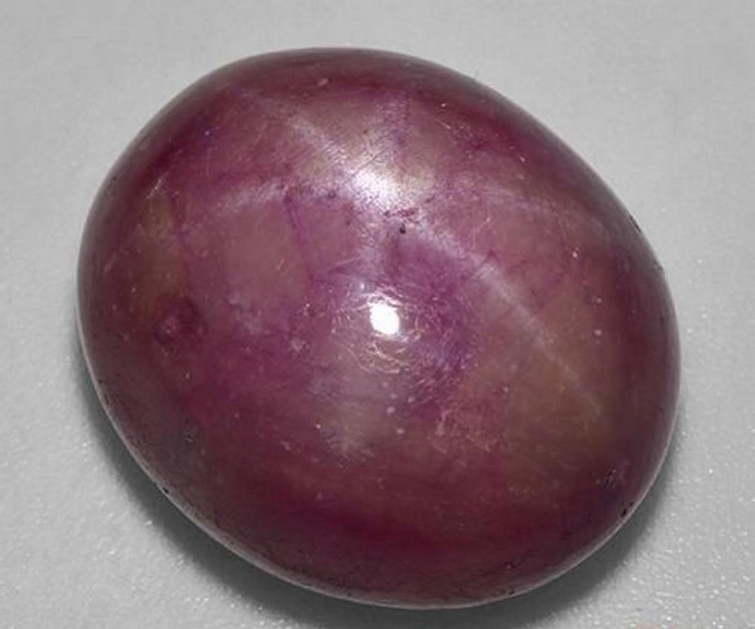 25.63 ct Oval Cabochon Natural Reddish Purple Star Ruby: 25.63 ct Oval Cabochon Natural Reddish Purple Star Ruby Introducing the Oval Cabochon Natural Reddish Purple Star Ruby, a striking gem with a rich reddish-purple hue and an eye-catching star effect. T
