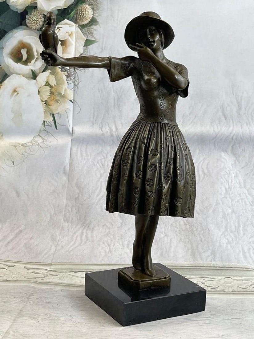 Elegant Young Lady Holding a Bird on her Outstretched Arm Bronze Statue: Elegant Young Lady Holding a Bird on her Outstretched Arm Bronze Statue. The delightful young woman is dressed in a classy and feminine sundress. Her chic sunhat rests on her head with her bob peeking