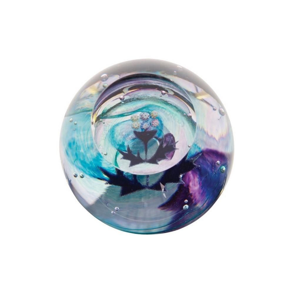 Highland Bloom Paperweight: Highland Bloom Paperweight A miniature glass paperweight featuring a detailed Scottish thistle set against a swirling backdrop of purple and blue. Crafted using hot glass techniques, the tiny flower s