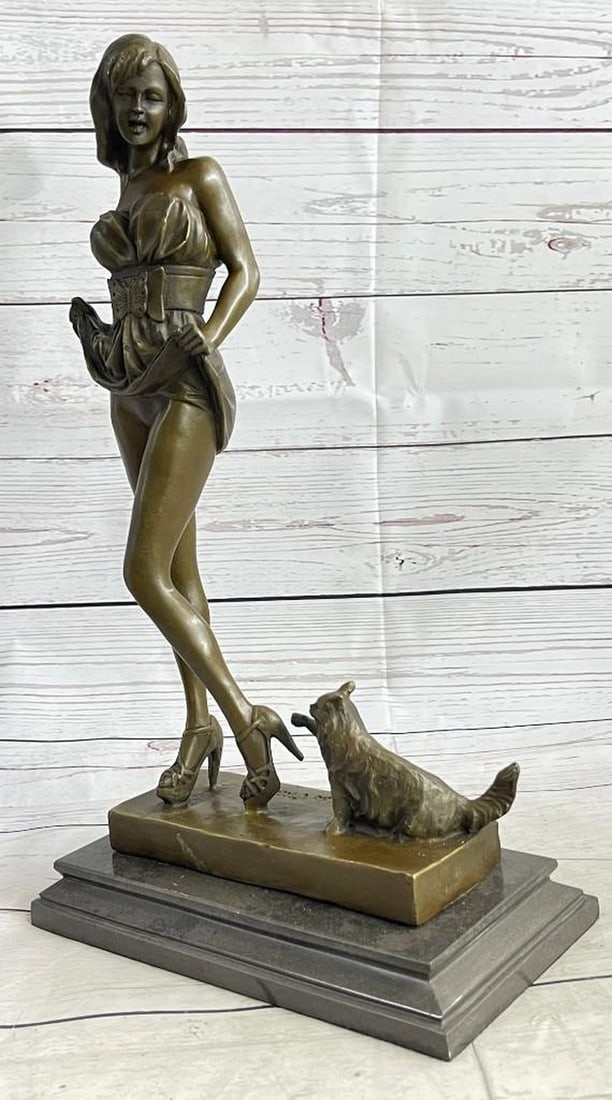 Bronze Sculpture of Woman with Kitten: Bronze Sculpture of Woman with Kitten An elegant bronze sculpture portraying a stylish woman standing gracefully in heels, gently lifting her dress as a playful kitten reaches up toward her feet. The 