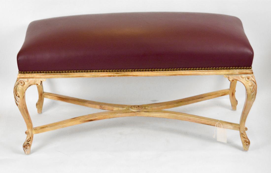 French Influenced "Leather" Bench: Carved giltwood legs and maroon seat. 37" W x 19" H. Guest House Guest Suite 2. NO RESERVE. This lot was formerly the property of well-known real estate developer Mr. Melvin Simon and his wife, Bren S