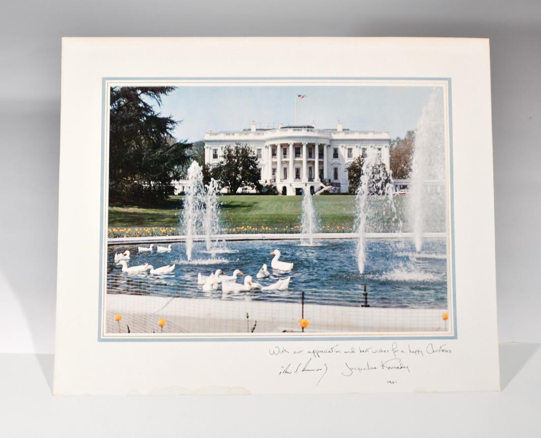 Kennedy White House Christmas Card: 1961 Kennedy Christmas Card. 14" x 17" tipped-in color photograph, obviously taken at a warm time of year with ducks swimming in pool in front of the White House. On the mat border "With our appreciat