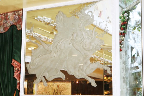 Etched Glass Mirror of Lady Riding a Bull: Inspired by the visual language of Green and Roman mythology, this contemporary Art Nouveau-style etched glass mirror features a woman sitting atop a charging bull. Designed by Warner LeRoy and Tavern