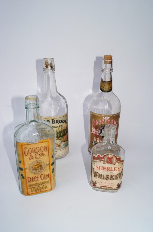 Four Antique Bottles: Sherley Whiskey, W. P. Leach & co. Gainesville, Texas, paper label; Liberty Bell Bourbon, Tucson, Arizona, paper label; Gordon Dry Gin ,paper label; Cedar Brrok Sour Mash, Santa Fe, New Mexico paper l