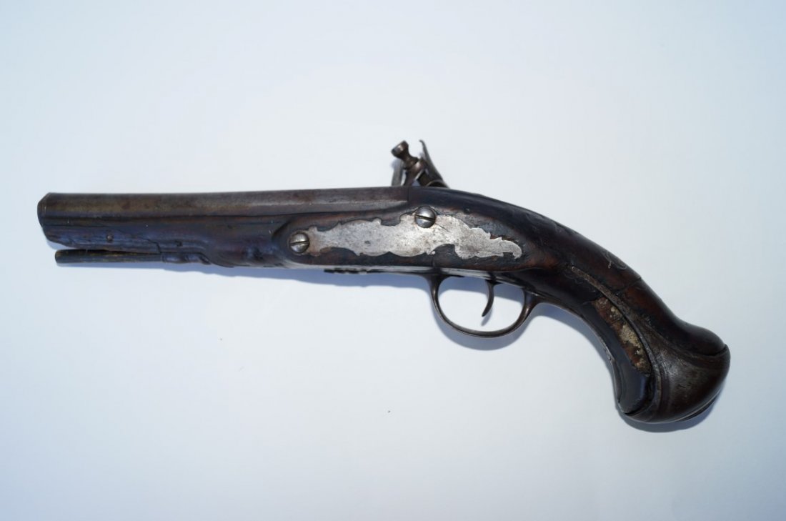 British Flintlock Pistol: Approx. 58 calibre. Silver wire inlay on grip. Steel grip cap. Lock work functioning. Initials H B C on a small plaque on the gun. Piece on grip is broken